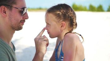 Parent applying sun cream to kid nose. Portrait of cute girl in suncream video