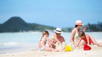 famille faisant un château de sable sur une plage blanche pendant les vacances d'été video