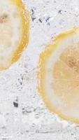 Soda water with ice cubes and sliced lemon slow motion vertical video. video