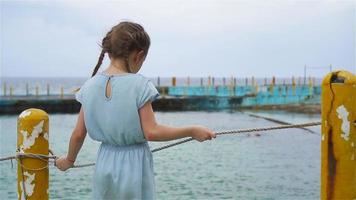 förtjusande liten flicka på strand under sommar semester. tillbaka se av unge med hav se. långsam rörelse video