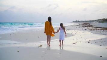 Little adorable girl and young mother at tropical beach in warm evening video