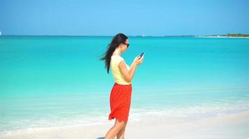 giovane donna uso Telefono durante tropicale spiaggia vacanza. turista utilizzando mobile smartphone. video