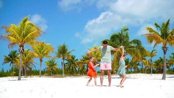contento familia a tropical playa tener divertida. padre y pequeño niños disfrutar hora juntos en blanco arena playa en su fiesta video