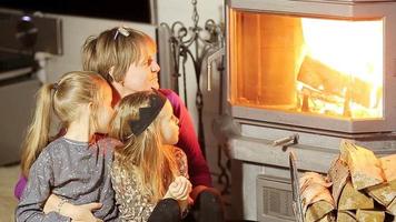 Grandmother and her two little granddaughters sitting by a fireplace in their family home on Xmas eve video
