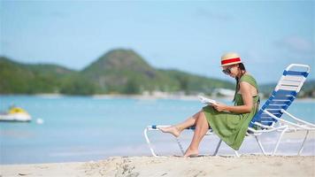 jeune femme lisant un livre sur des chaises longues pendant une plage blanche tropicale video