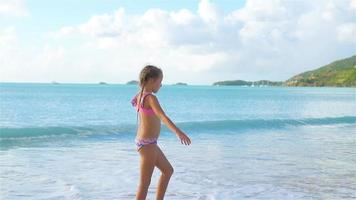 pequeño activo niña haciendo volteretas en el playa a puesta de sol. lento movimiento video