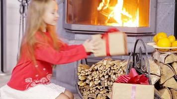 Smiling nice girl opening christmas present near fireplace video