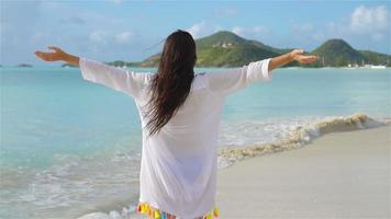 Young beautiful woman having fun on tropical seashore. Happy girl walking at white sand tropical beach. SLOW MOTION video