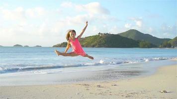 aktiva liten flicka på strand har en massa av roligt. söt unge framställning sportig övningar på de havsstrand video