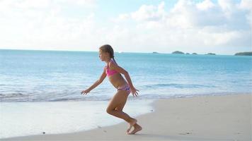 adorável feliz pequeno menina caminhando em branco de praia. lento movimento vídeo video