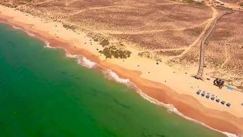 zangão panorâmico registro sobre vendaval de praia dentro Portugal com topo Visão em litoral video