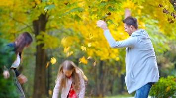 Young smiling family throwing leaves around on an autumn day outdoors video