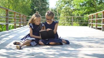 adorabile poco scuola ragazze con Appunti e matite all'aperto. indietro per scuola. video