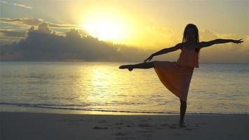 Silhouette of adorable little girl on white beach at sunset. SLOW MOTION video