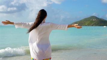 Young beautiful woman having fun on tropical seashore. Happy girl walking at white sand tropical beach. SLOW MOTION video