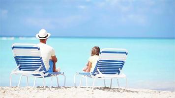 Father and daughter on tropical beach sitting on chaise-longue enjoying the view of Atlantic Ocean video