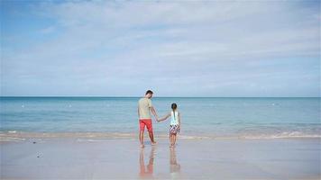 familia en la playa tropical caminando juntos en la playa tropical de la bahía de carlisle con arena blanca y agua turquesa del océano en la isla de antigua en el caribe.