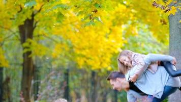 Lycklig familj i höst parkera utomhus. Lycklig barn ans pappa kasta löv runt om på ett höst dag utomhus video