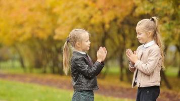 Niñas adorables que se divierten en un día cálido en el parque de otoño al aire libre video