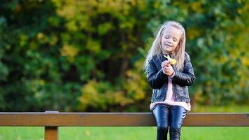 portrait d'une adorable petite fille avec une feuille jaune à l'extérieur lors d'une belle journée d'automne video