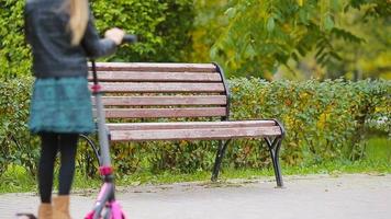 moeder en weinig meisje Aan scooter genieten vallen dag in herfst park buitenshuis video