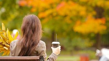 mooi vrouw drinken koffie in herfst park onder vallen gebladerte video