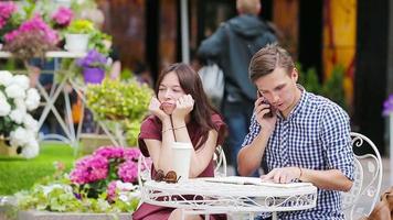 restaurante turistas casal às ao ar livre cafeteria. jovem menina triste às dela namorado Porque ele é ocupado com tarefas video