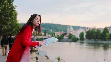 glücklich jung Frau mit ein Stadt Karte im Europa Hintergrund berühmt Brücke. Reise Tourist Frau mit Karte draußen während Ferien im Europa. video