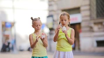 adorabile poco ragazze mangiare gelato all'aperto a estate. carino bambini godendo vero italiano gelato vicino gelateria nel Roma video