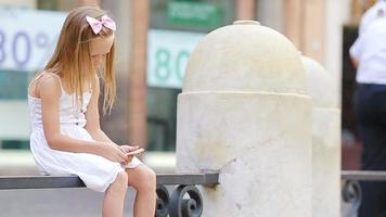 adorable pequeño niña con Teléfono móvil a calentar día al aire libre en europeo ciudad cerca famoso fontana di trevi video