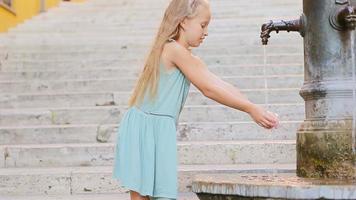 Little adorable girl drinking water from the tap outside at hot summer day in Rome, Italy video