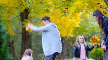 joven familia tener divertido lanzamiento hojas alrededor en un otoño día al aire libre video
