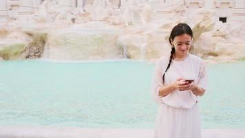 joven mujer con inteligente teléfono cerca famoso fontana di trevi video