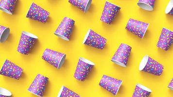 Paper cups with colorful sprinkles pattern diagonally arranged on yellow background photo