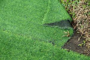 An incomplete green artificial turf used for covering sport arena or garden. photo