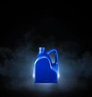 Blue bottle of engine oil on black background with smoke photo