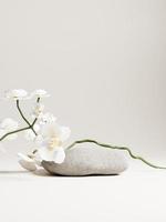 3d stone display podium with white orchid flower against beige background. 3d rendering of realistic presentation for product advertising. 3d minimal illustration. photo