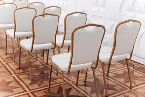 Row of festive elegantly gold metal chairs with white cloth indoors hall. photo