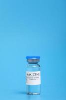 ampoule with Covid-19 vaccine in laboratory. to fight the coronavirus sars-cov-2 pandemic. Glass vial medical close-up isolated on a blue background. photo