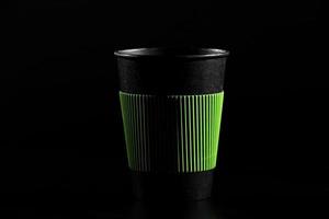 a glass of hot tea or coffee. Black paper glass with a lid on a black background. side view photo