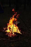 Cooking outdoors in field conditions. Cauldron on a fire in the forest. Cooking at the stake while traveling. Tripod with a bowler hat on a fire on picnic. Conceptual travel, trekking and adventure photo