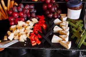gray board with different types of cheese, fresh grapes and jam. Dinner or aperitif party concept. photo