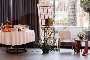 easel with wooden Stylish Board list seating plan for wedding reception. Vintage luxury wedding. table with fruit and champagne for guests photo
