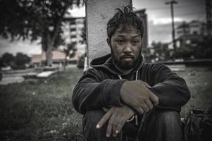 un hombre asiático no tiene hogar en la calle lateral, un extraño tiene que vivir solo en la calle porque no tiene familia. foto