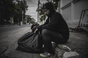 un hombre asiático no tiene hogar en la calle lateral, un extraño tiene que vivir solo en la calle porque no tiene familia. foto