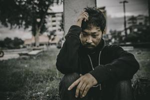 un hombre asiático no tiene hogar en la calle lateral, un extraño tiene que vivir solo en la calle porque no tiene familia. foto