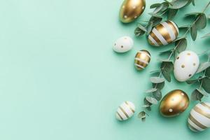 Easter eggs painted in gold and eucalyptus branches on a soft green background. photo