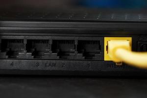 inalámbrico módem enrutador con amarillo cable y lan Puerto para conexión en un negro antecedentes. foto