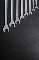 A set of wrenches on a textured black background in a row. photo