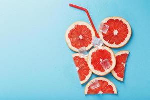 A composition of grapefruit slices and ice cubes with a blue background in the form of a refreshing drink photo